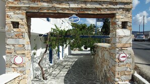 A stone archway leading to a building with a sign for 'Homer's Inn'. - Homer's Inn Hotel (Ios)