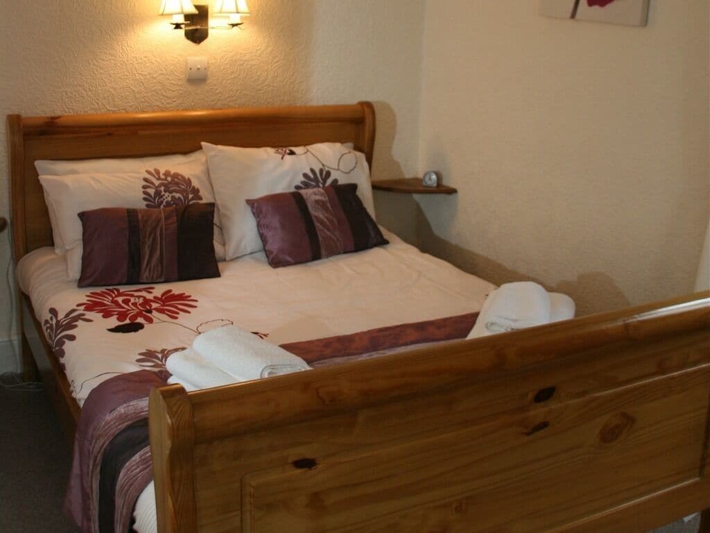 A neatly made bed with a floral bedspread, two pillows, and a wooden headboard.