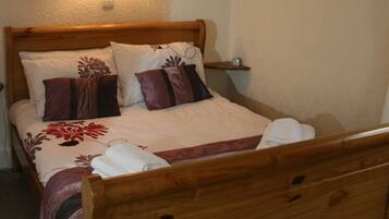 A neatly made bed with a floral bedspread, two pillows, and a wooden headboard.
