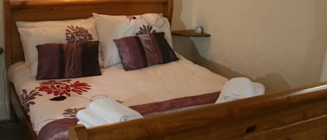 A neatly made bed with a floral bedspread, two pillows, and a wooden headboard.