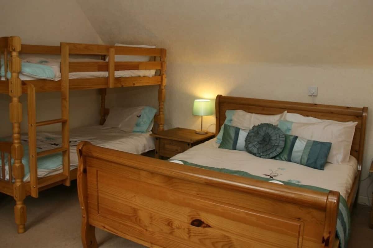 A room with two wooden bunk beds and a single bed with a wooden headboard.