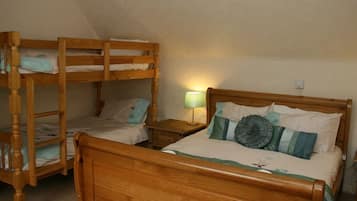 A room with two wooden bunk beds and a single bed with a wooden headboard.