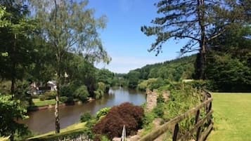 Une vue sur la rivière, avec une clôture en bois, de la verdure et un ciel dégagé.