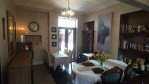 A dining area with a chandelier, a clock, and a bookshelf. - Tyrosa Rooms   (Cardiff)