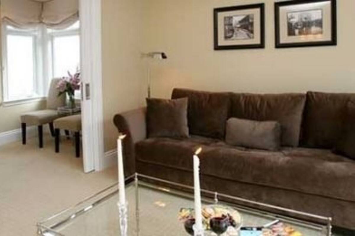 A living room with a brown sofa, a glass coffee table, and two framed pictures on the wall.