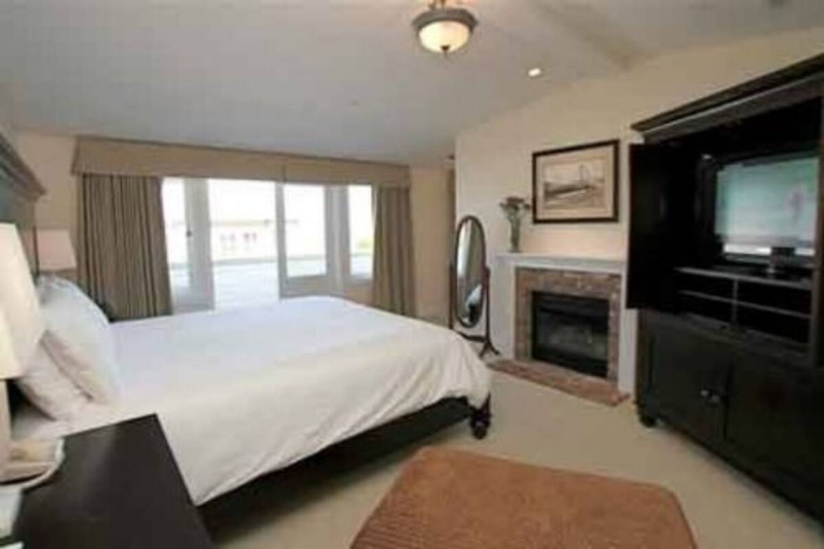 A hotel room with a bed, a fireplace, a television, and a large window.