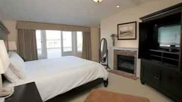 A hotel room with a bed, a fireplace, a television, and a large window.