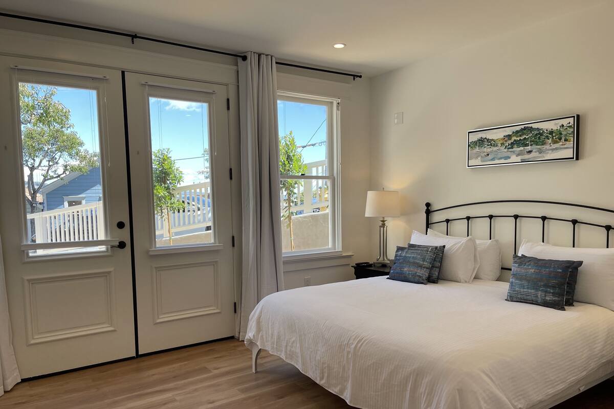 A bedroom with a bed, a nightstand, a lamp, and a painting on the wall.