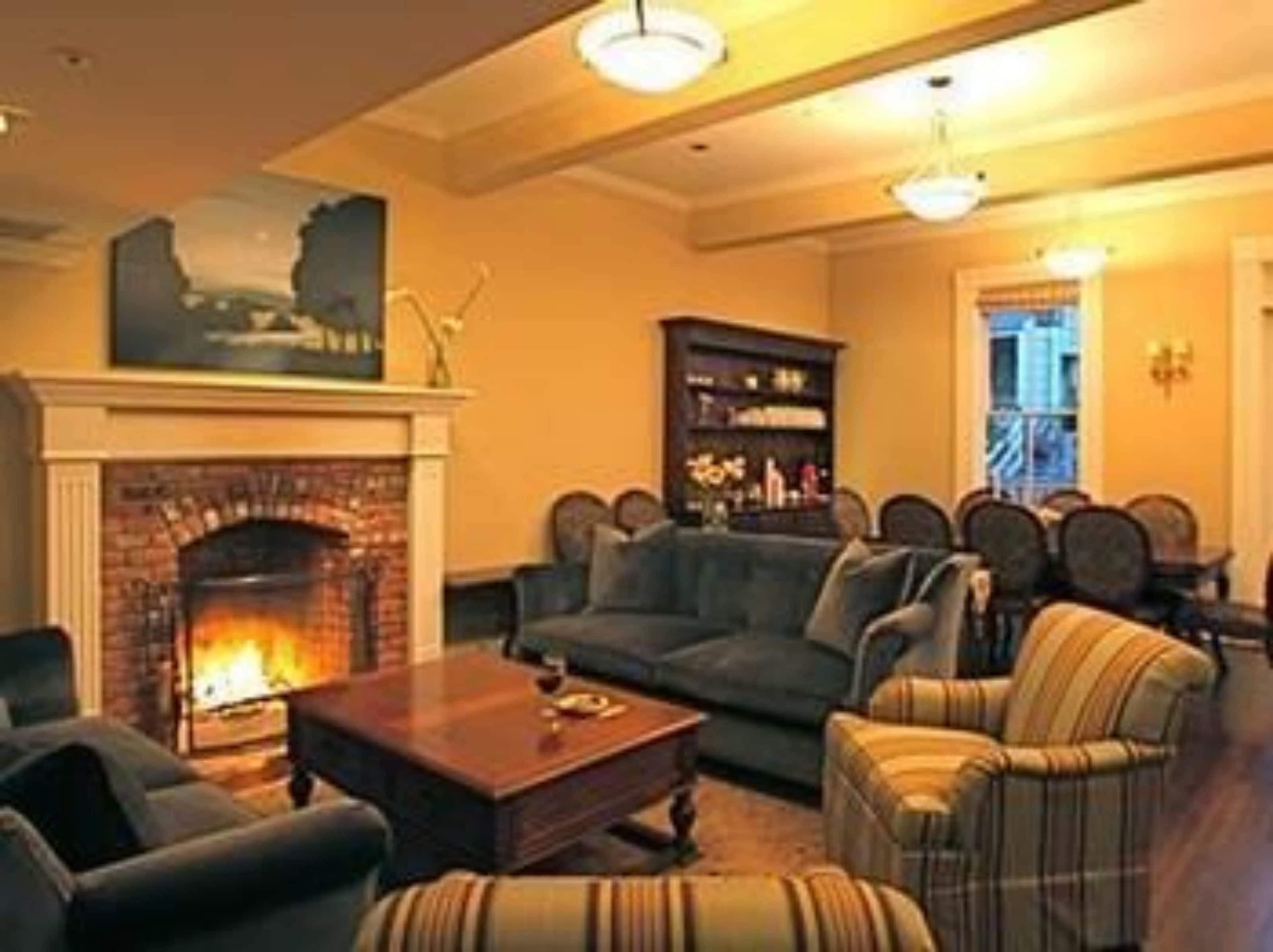 A cozy living room with a fireplace, comfortable seating, and a bookshelf.