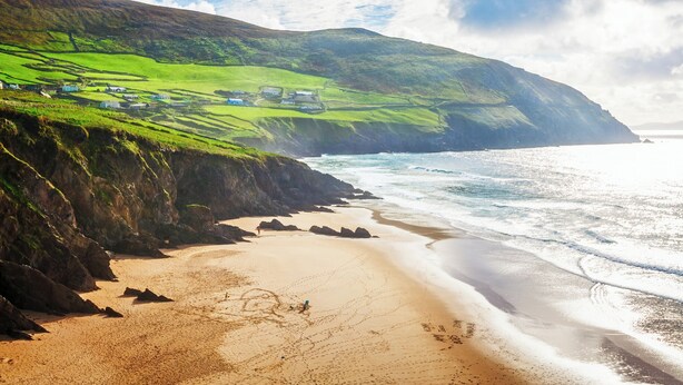 A coastal landscape with green hills, a sandy beach, and a rocky shoreline. - Killarney Heights Hotel (Killarney)