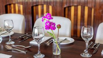 Une table à manger dressée avec de beaux verres transparents, un petit vase contenant une seule fleur violette et des couverts soigneusement disposés.