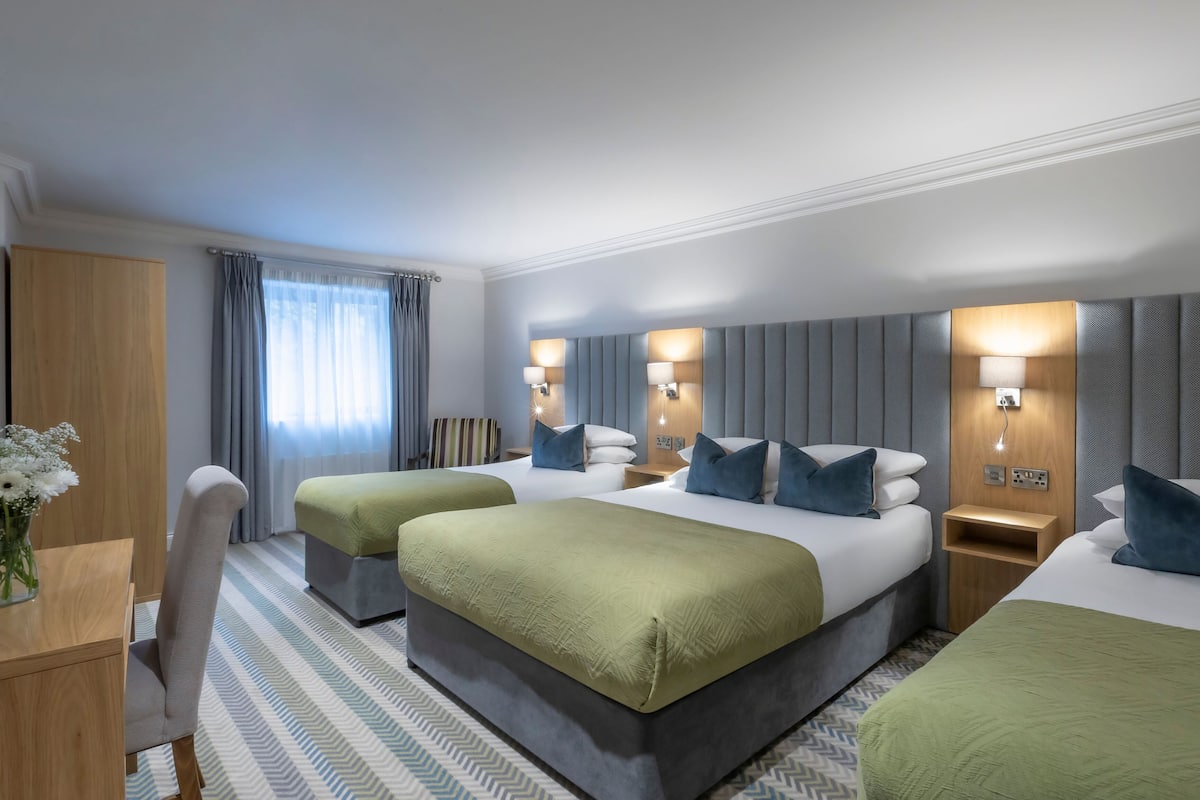 A hotel room with two beds, a desk, and a chair.