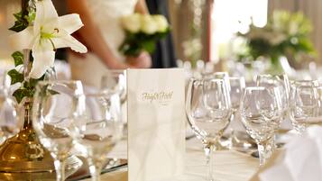A table set with wine glasses, a menu, and a vase with a white flower.