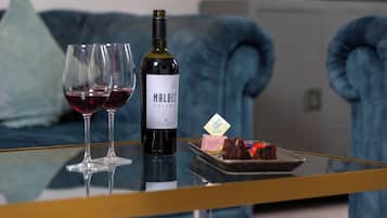 Eine Flasche Malbec, zwei Weingläser und ein Dessert auf einem Glastisch.