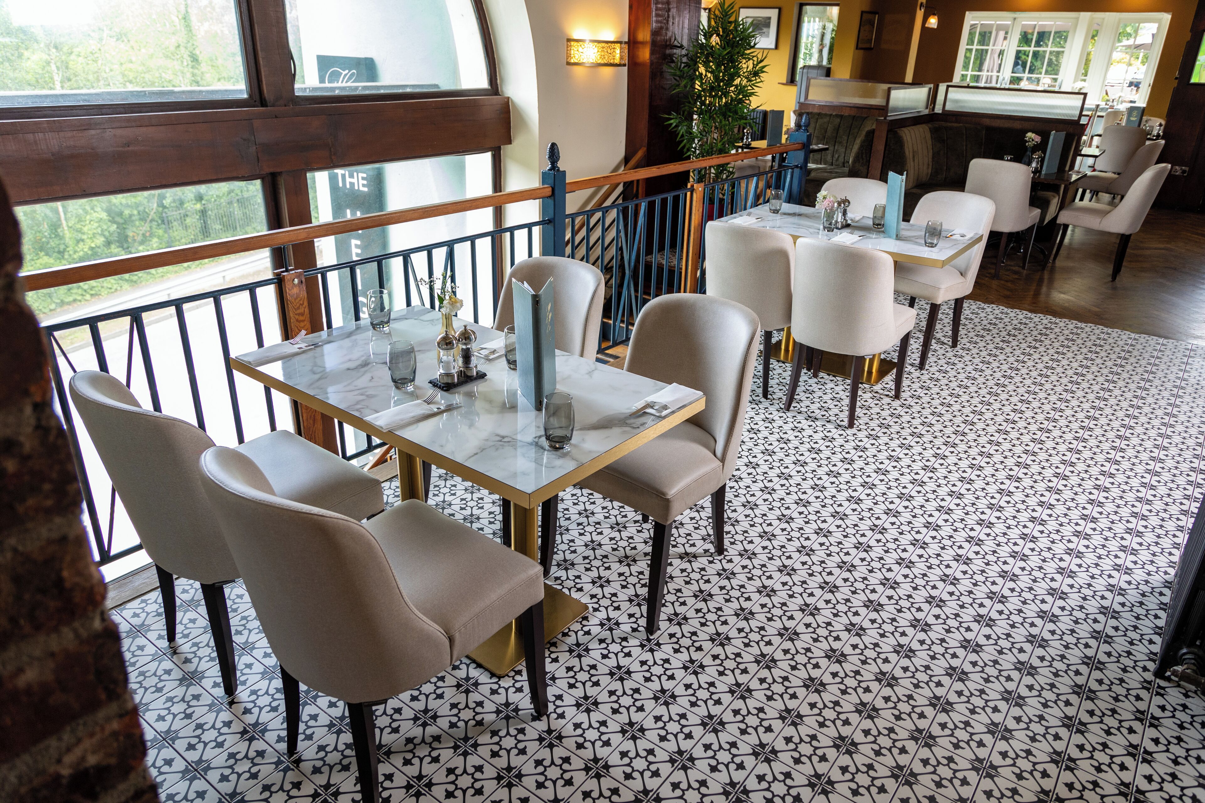 A restaurant with a terrace, tables with chairs, and a patterned floor.