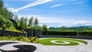 A landscaped garden with a stone spiral pathway and seating area. - Killarney Heights Hotel (Killarney)