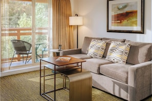 A modern living room with a sofa, a coffee table, a lamp, and a framed abstract painting.