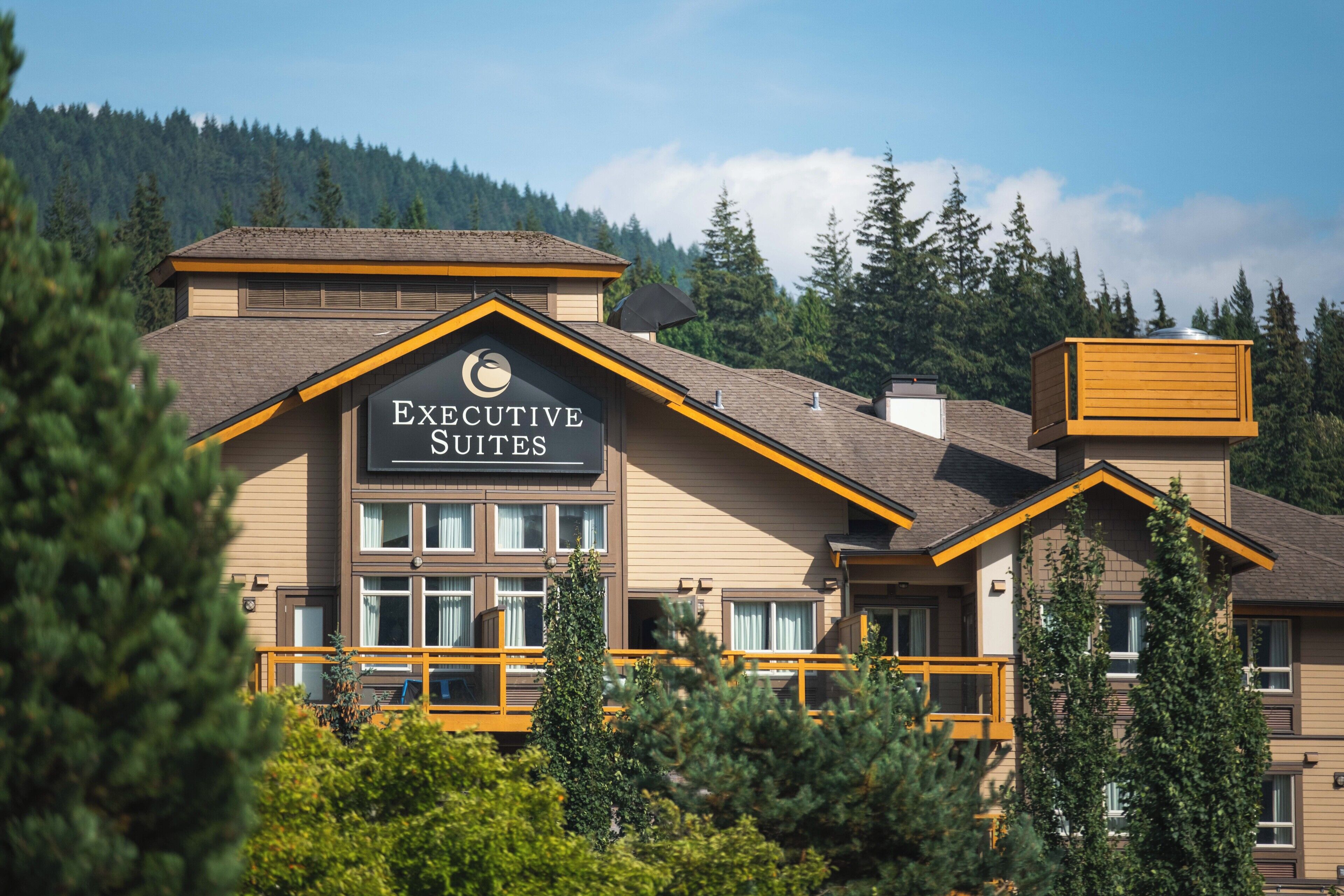 A hotel with a sign reading 'Executive Suites,' featuring a modern architectural design with multiple windows and a balcony.
