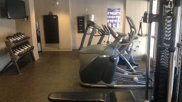 A gym with treadmills, dumbbells, and weight machines.