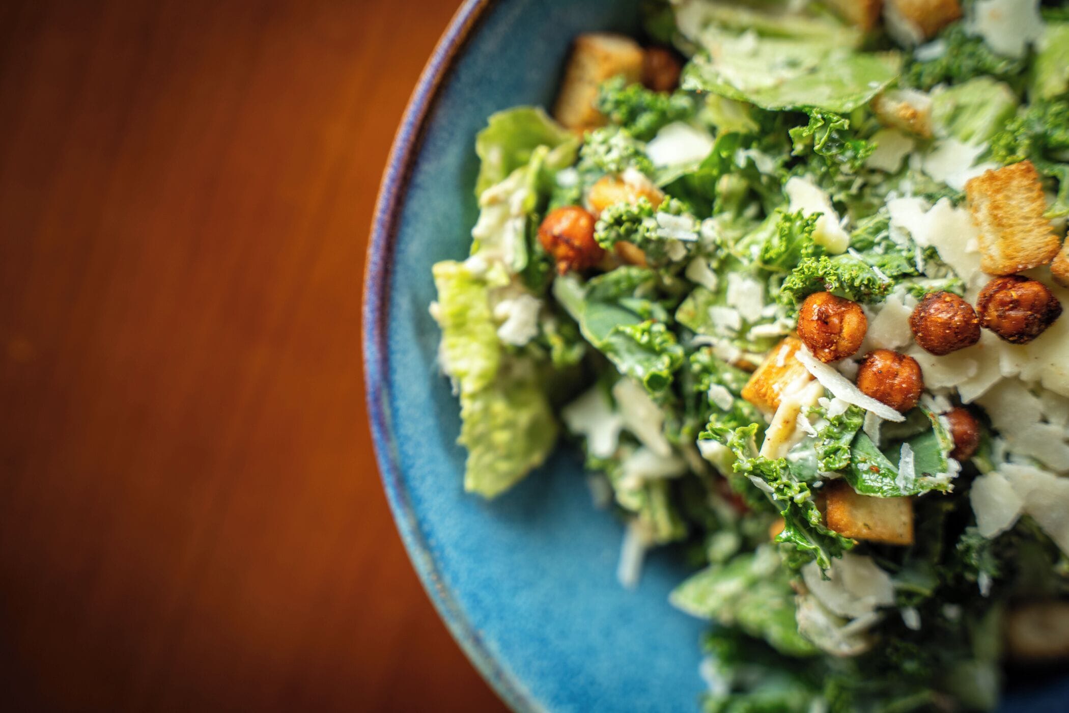 Primer plano de una ensalada con lechuga, crotones y nueces.