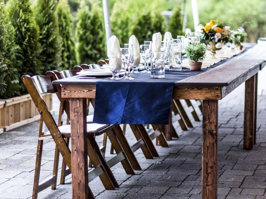 An outdoor dining table set with chairs, a tablecloth, and a potted plant.