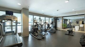 Une salle de sport équipée de tapis de course, de vélos elliptiques et de matériel de musculation.