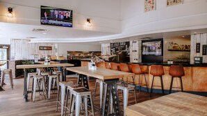 A modern bar area with stools, a television screen, and a bar counter. - Executive Suites Hotel & Resort, Squamish (Squamish)