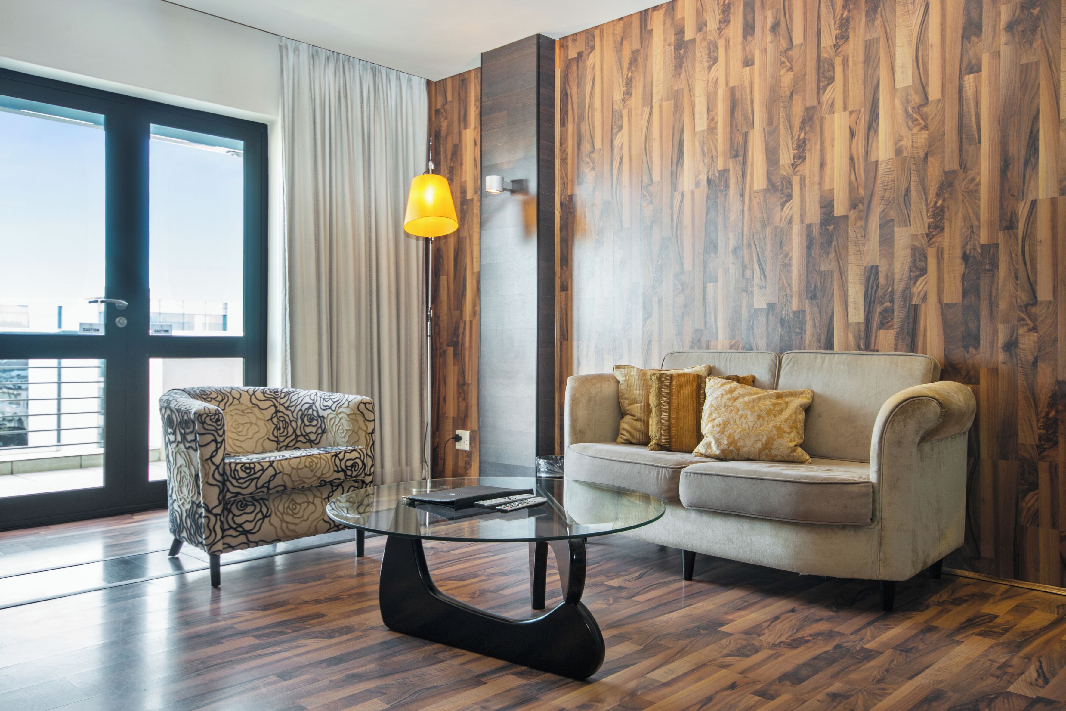 A modern living room with a sofa, armchair, and glass coffee table.