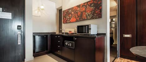 A modern kitchen with a microwave, refrigerator, and a large floral artwork on the wall.
