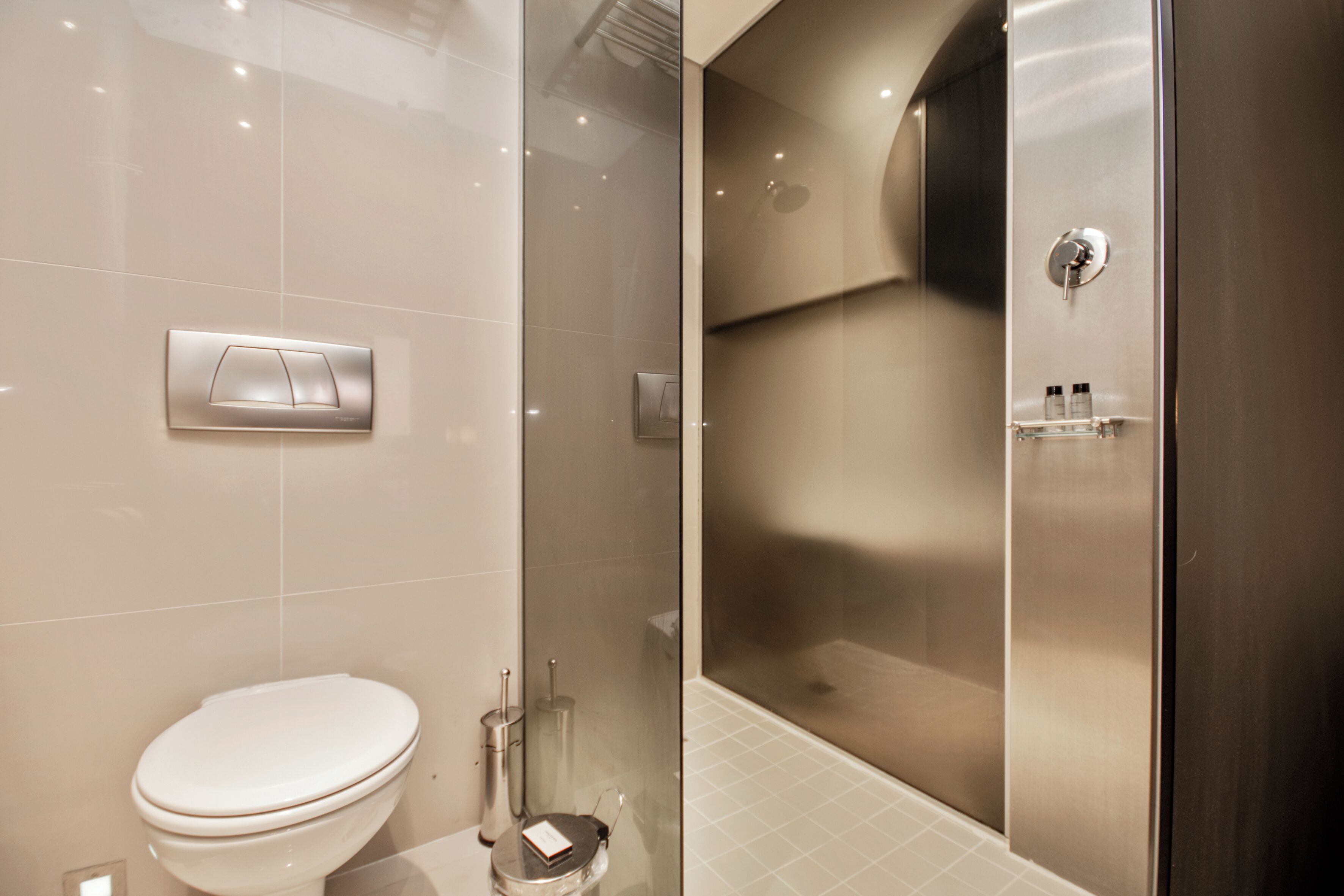 Un baño moderno con inodoro, cabina de ducha y mampara de vidrio.