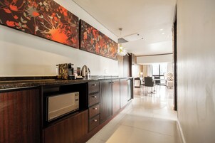 A modern kitchen with a built-in dishwasher, a coffee machine, and a large decorative wall piece.
