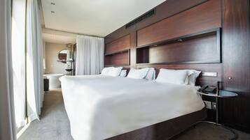 Una cama grande con sábanas blancas, una mesita de noche con lámpara y un cabecero de madera.