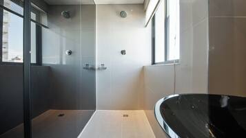 Un baño moderno con ducha de vidrio, una bañera independiente y un amplio ventanal que proporciona luz natural.