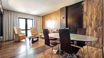 A modern hotel room with a wooden floor, a round dining table, and a sofa.