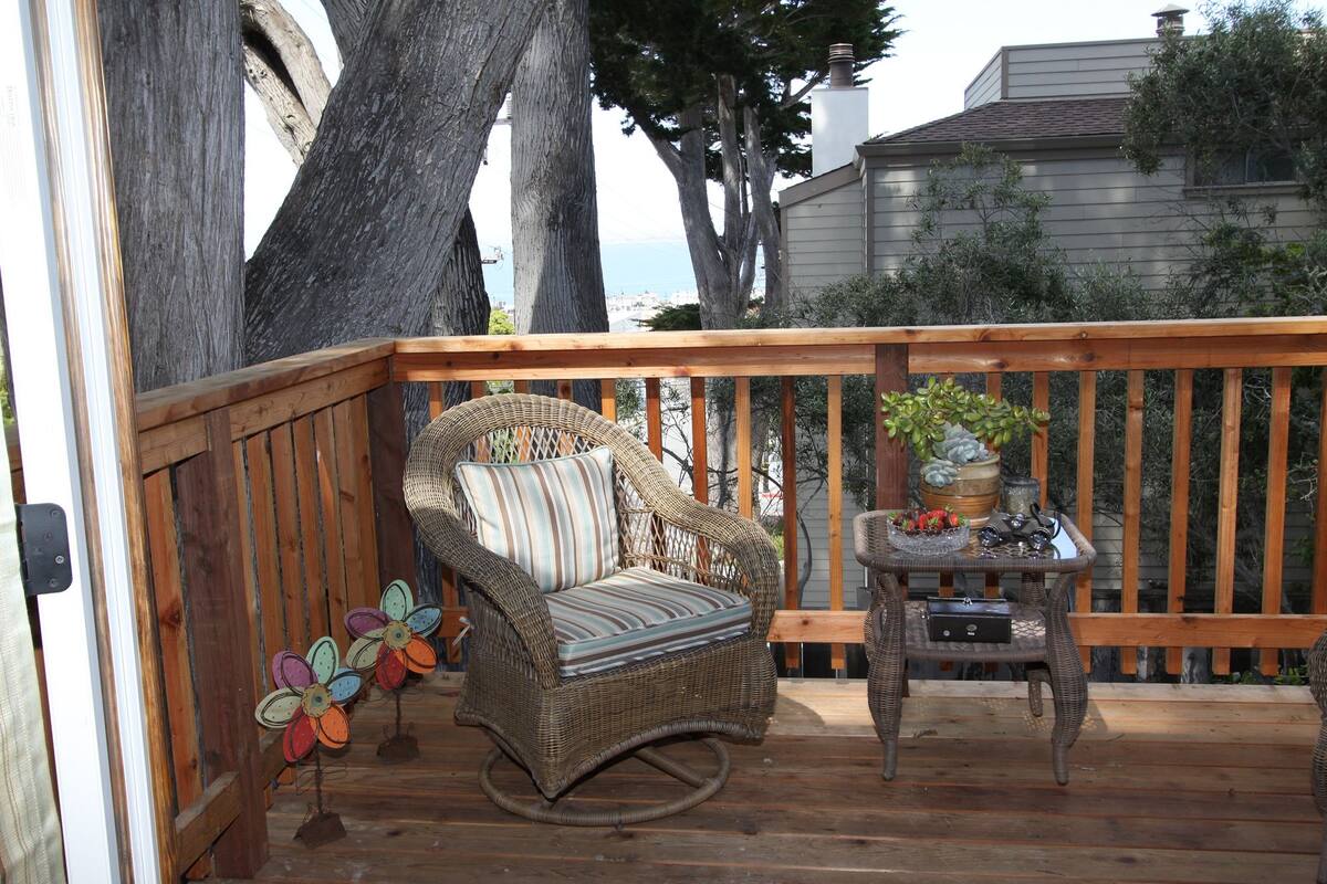 A wooden deck with wicker furniture, including a chair and a small table with decorative items.
