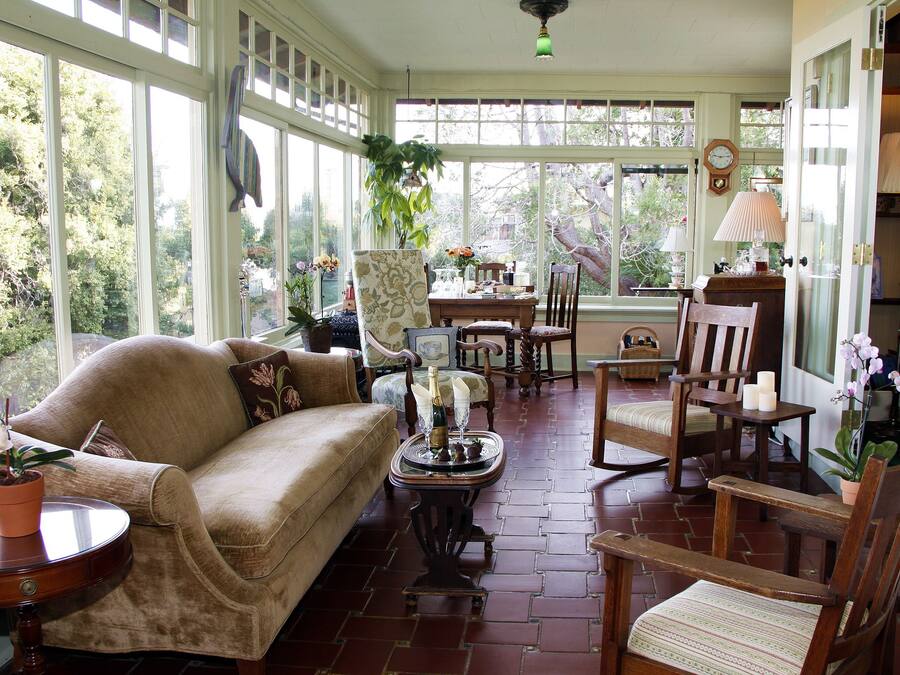 A sunlit room with a sofa, chairs, a table, and a potted plant.