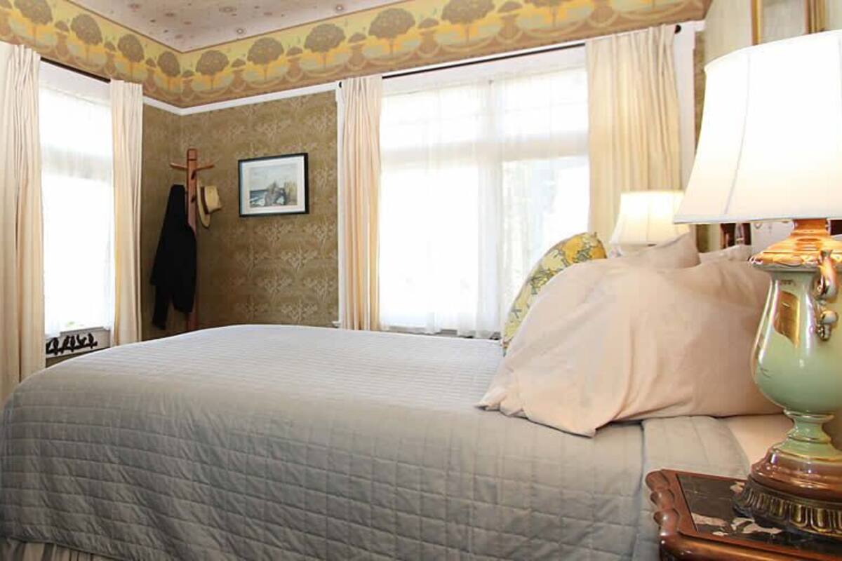 A bedroom with a bed, a dresser, a mirror, and a lamp.