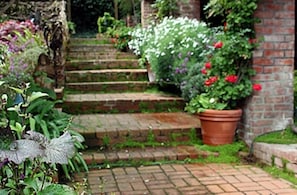 Un jardin avec un chemin en briques menant à un mur en briques.
