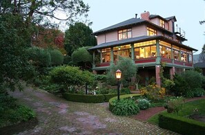 A large, two-story house with a covered porch and a garden. - Jabberwock Inn (Monterey)