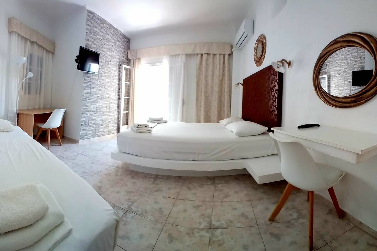 A hotel room with a bed, a desk, a chair, a TV, and a bathroom.