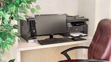 A computer desk with an HP desktop computer, a monitor, keyboard, and printer.