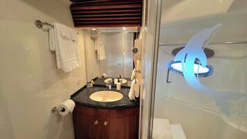 A modern bathroom with a glass-enclosed shower, a wooden vanity, a sink with a faucet, and a mirror.