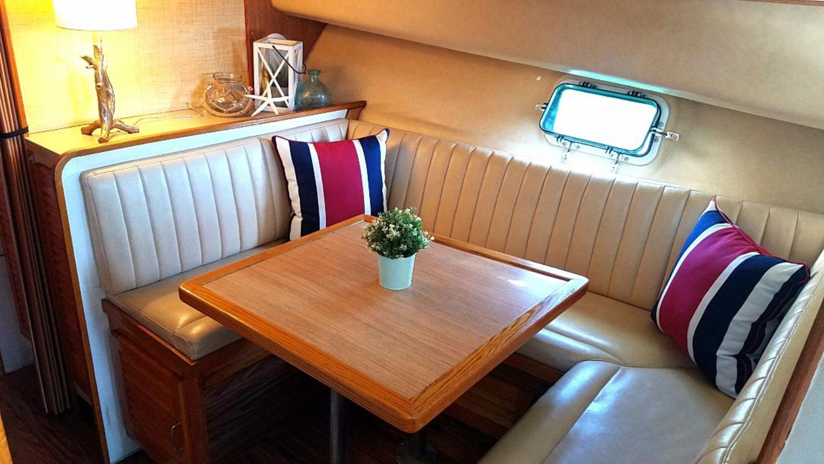 Un intérieur compact et bien éclairé, avec une table en bois, des sièges confortables, une petite plante en pot et une fenêtre donnant sur un beau paysage.