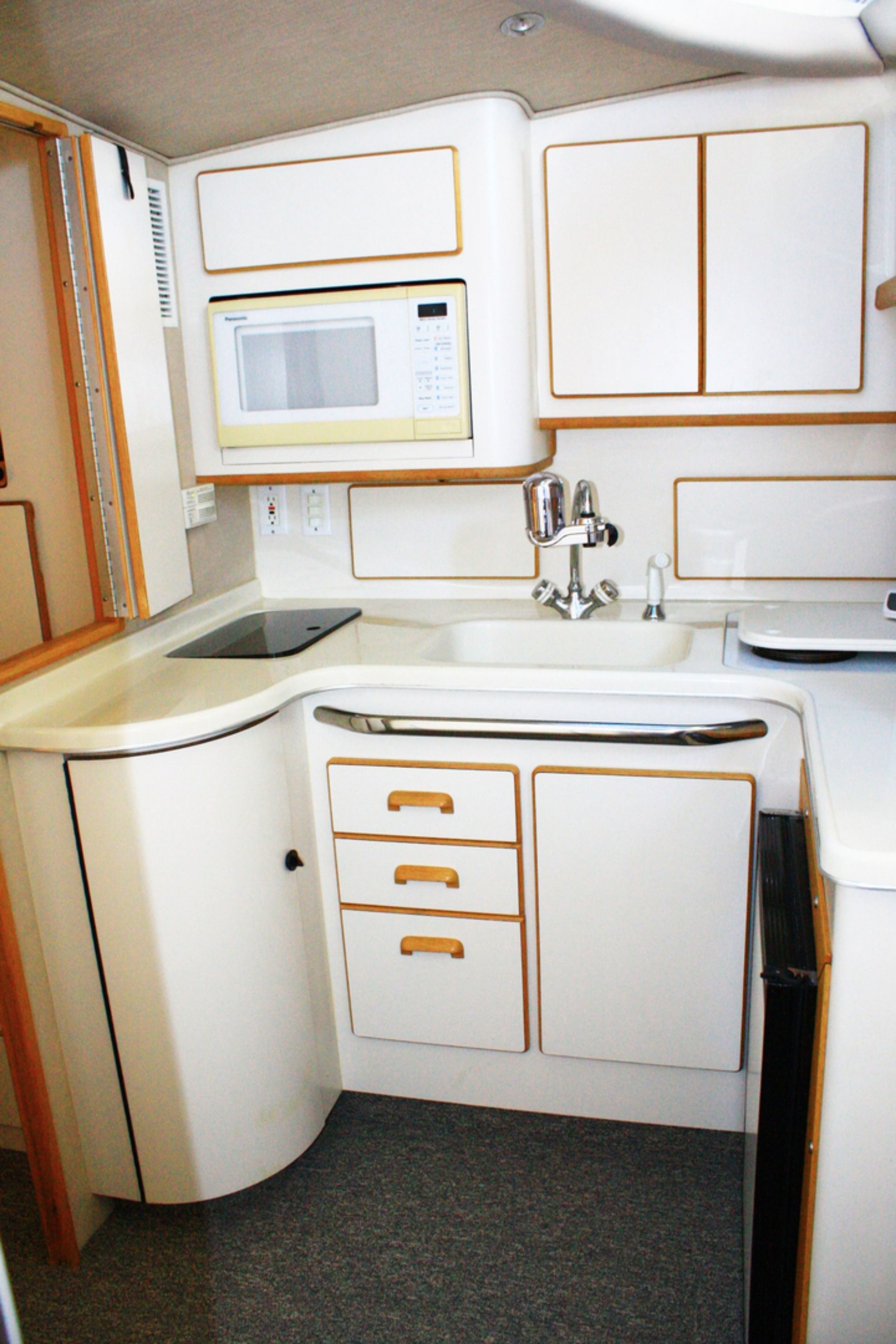 Una kitchenette compacta equipada con microondas, lavamanos y armarios de almacenamiento.