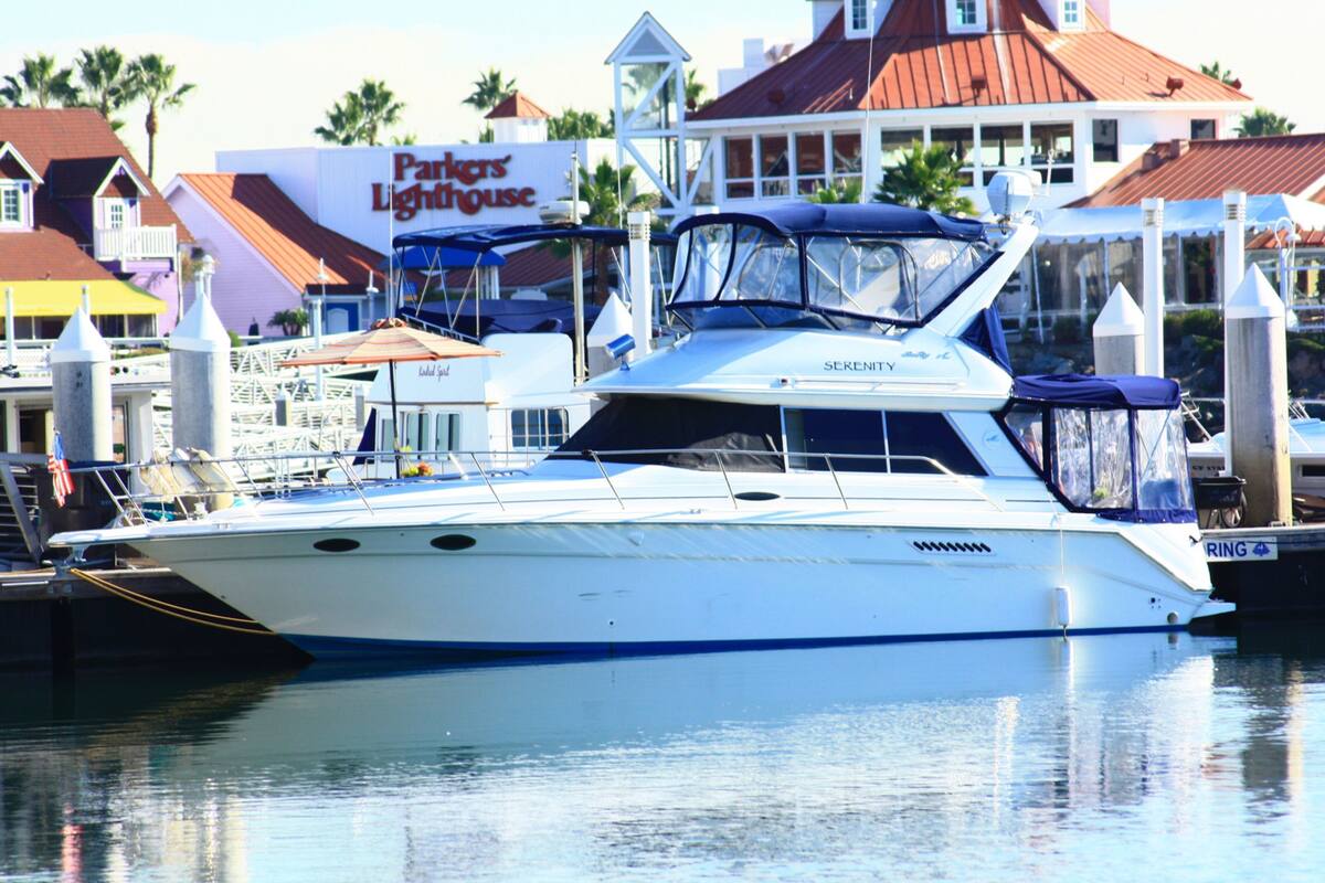 A white yacht docked at a marina with a sign for "Parkers' Lighthouse" in the background.