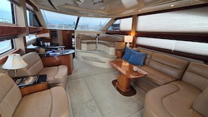 Interior de un yate con comedor, asientos y una pequeña cocina.