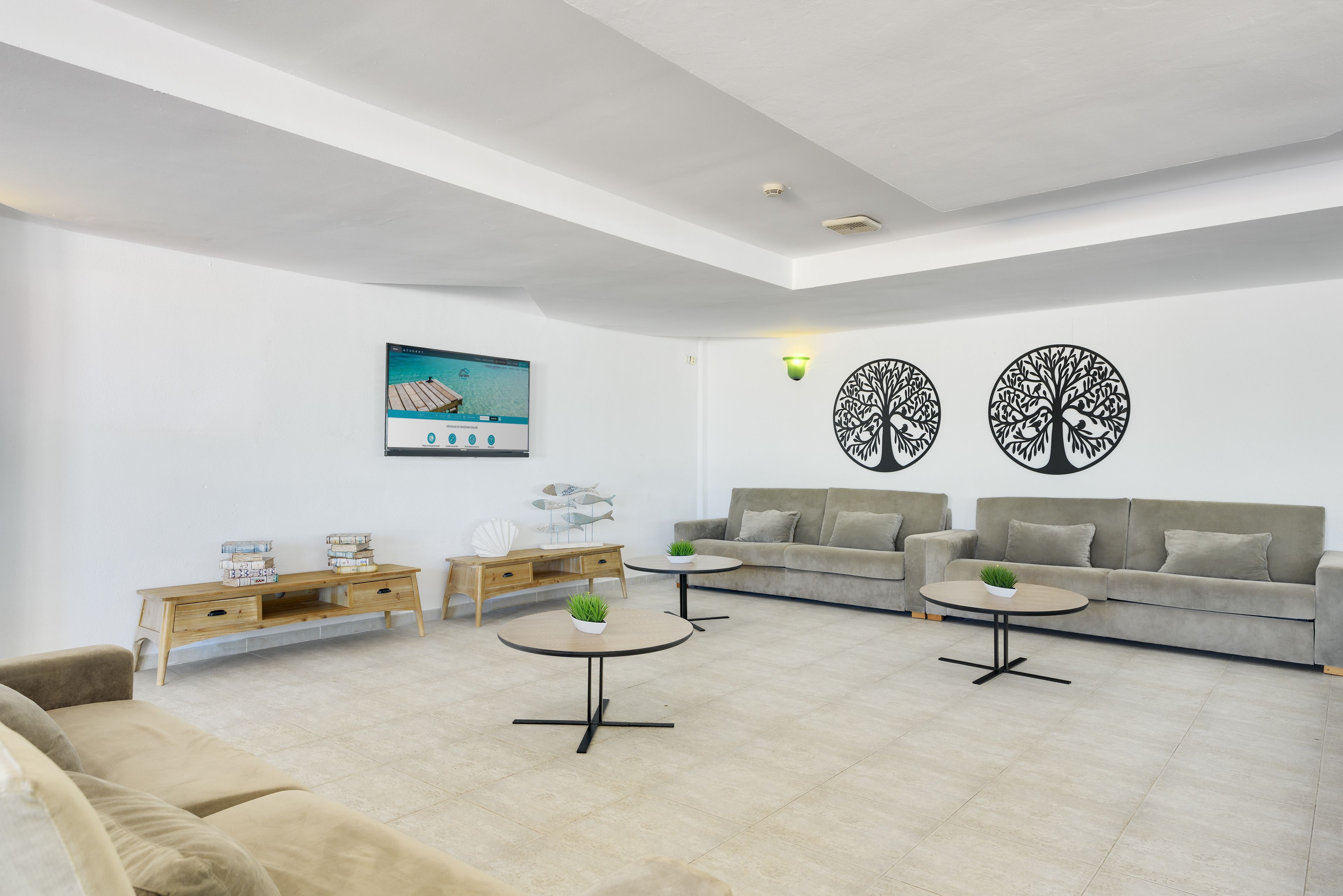 A modern living room with a sofa, two coffee tables, a wooden side table, and decorative wall art.
