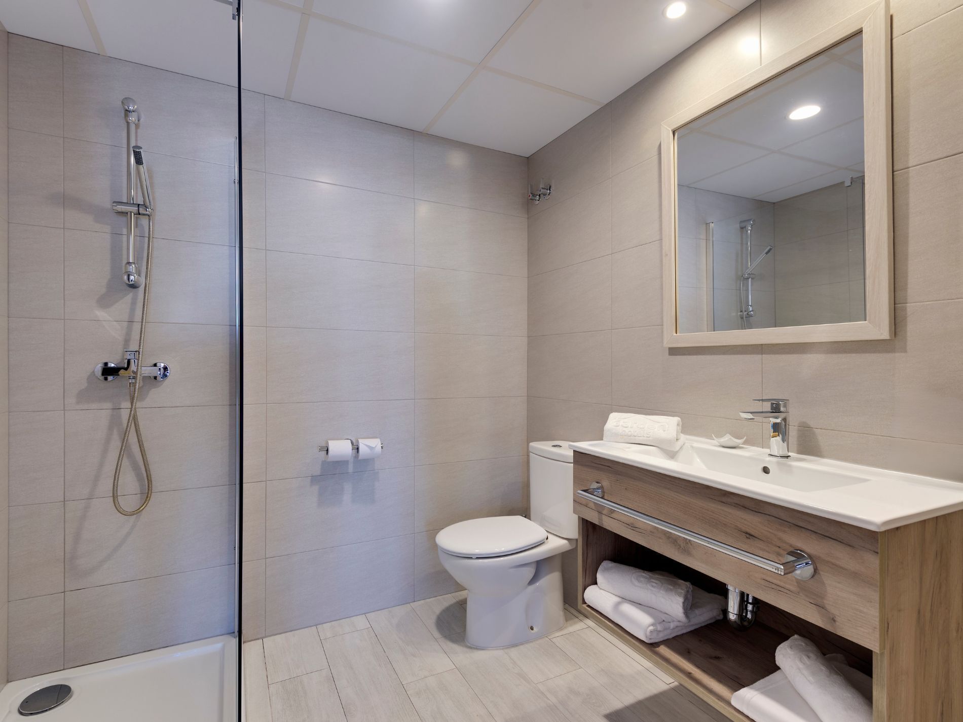 Een moderne badkamer met een douche, toilet en wastafel.