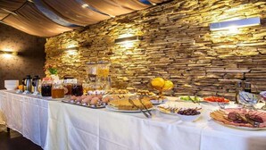 Una mesa de buffet con diferentes alimentos y bebidas, con un fondo de pared de piedra.
