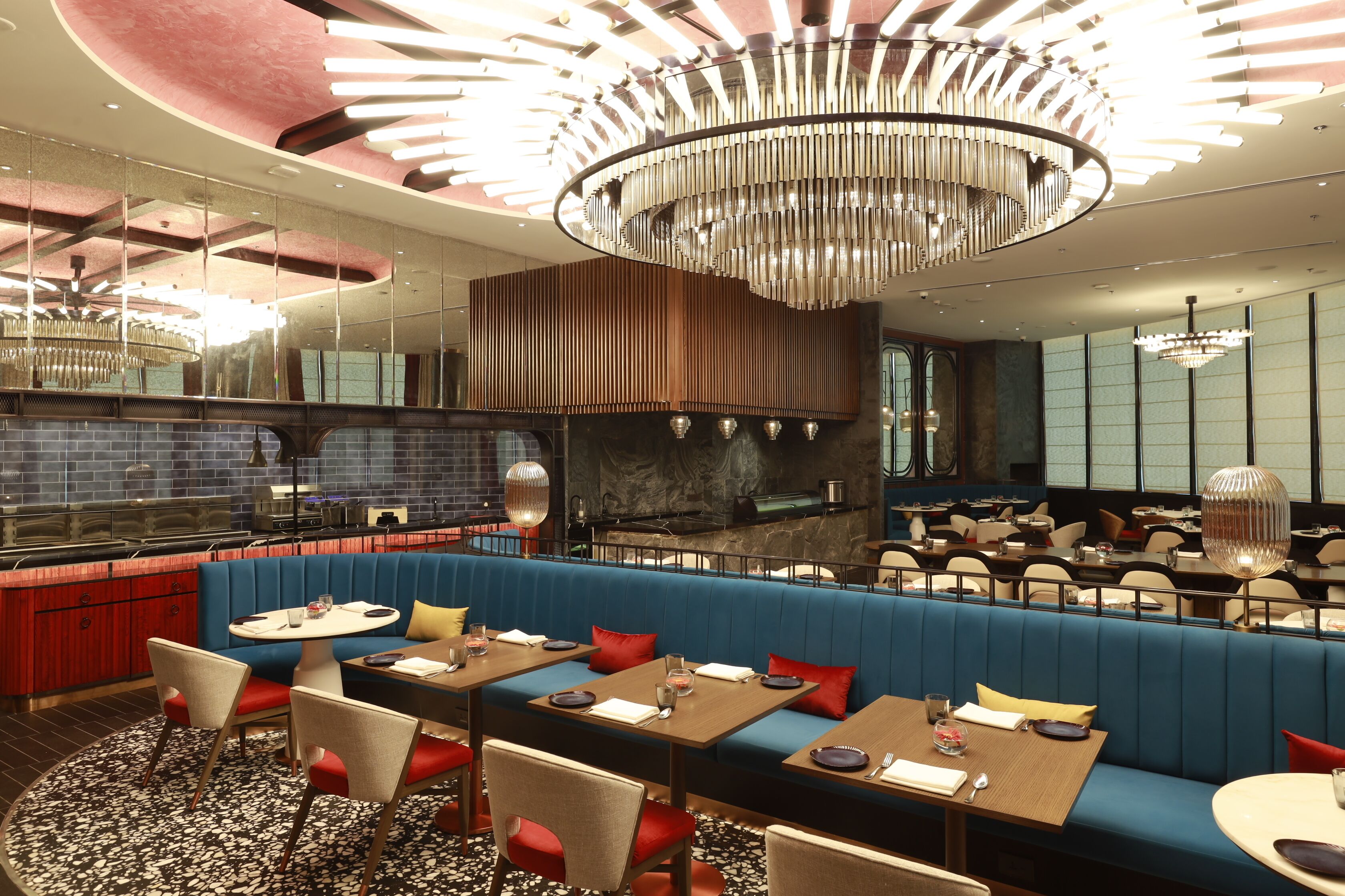 Ein modernes Restaurant mit blauen Sitzbänken, Holztischen und einer zentralen Bar.